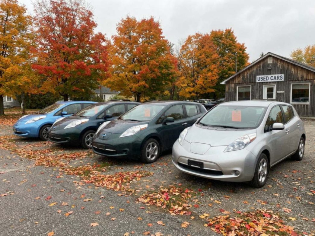 Used electric cars lined up on a Canadian dealer lot in autumn